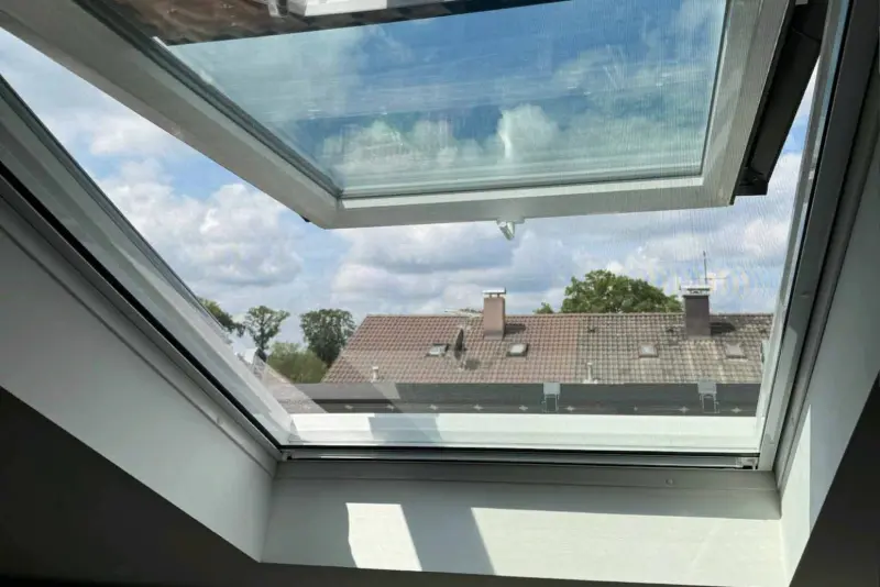 Geöffnetes Dachfenster mit Blick über die Dächer der Nachbarschaft
