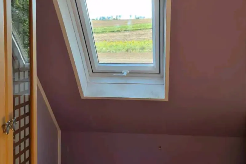 Eingebautes Dachfenster mit hellem Holzrahmen und Blick ins Grüne